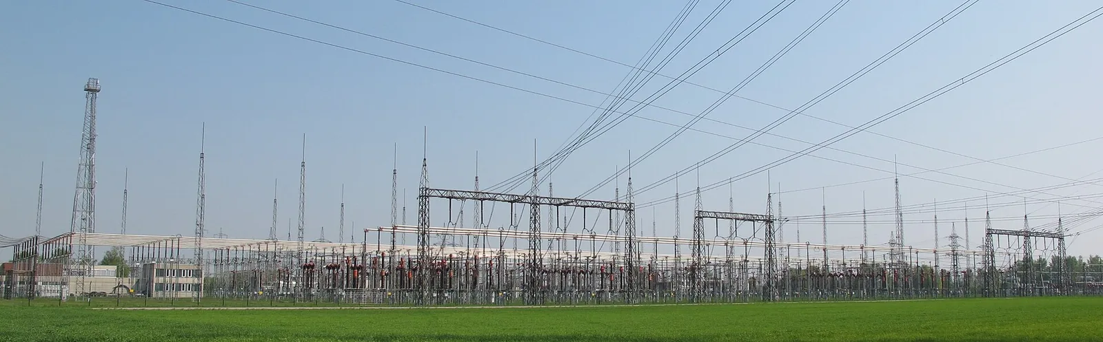 Panorama einer 380-Kilovolt-Freiluftschaltanlage hinter einer Wiese